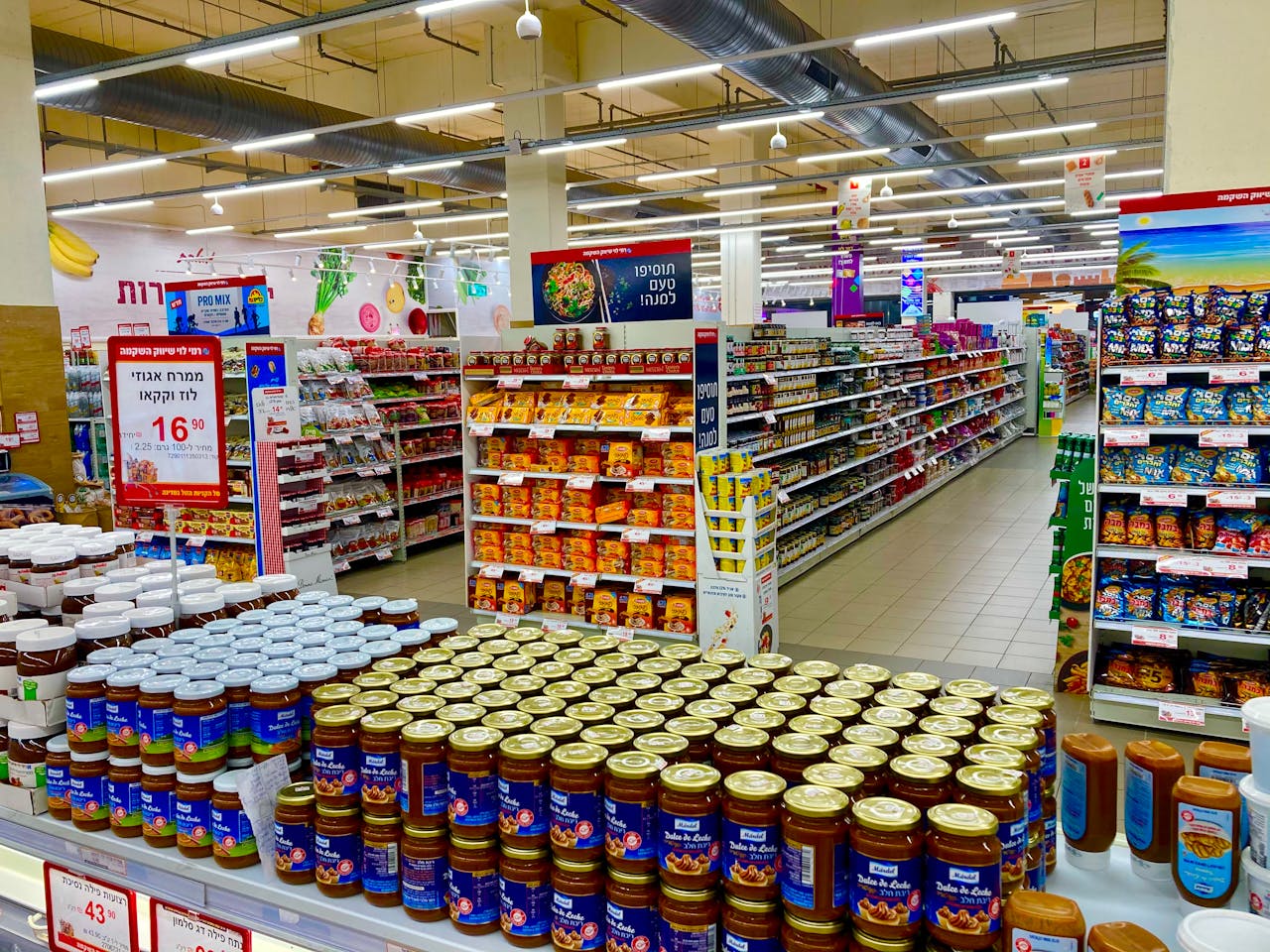 Wide view of a fully stocked supermarket aisle with jars and various products on shelves.