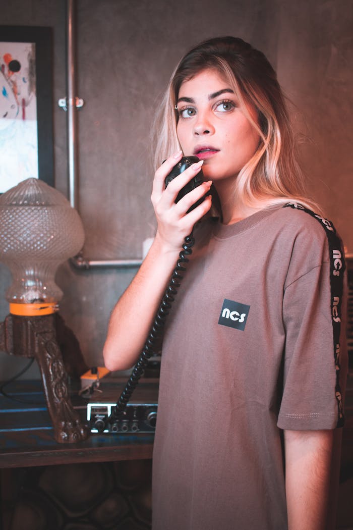 Stylish young woman in casual wear holding a retro microphone indoors.