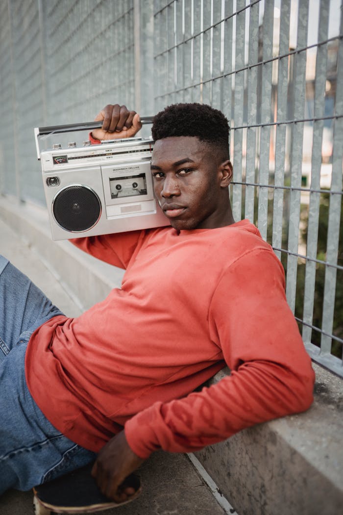 Stylish young man with vintage boombox sitting casually in urban setting.